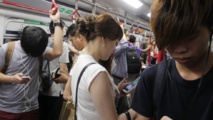 Chinos mirando sus teléfonos en el metro Chinos mirando sus teléfonos en el metro