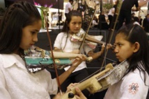 Unas niñas tocan violines hechos con materiales reciclados
