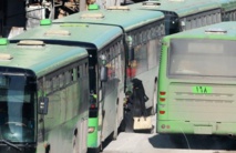 La gente sube a los autobuses en el barrio de As Sukkari, en Alepo, para ir a Idlib