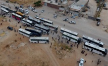 Los milicianos y sus familias suben a los autobuses