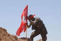 Un miliciano de las unidades de movilización popular pone su bandera en Al Baaj Un miliciano de las unidades de movilización popular pone su bandera en Al Baaj