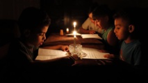 Niños palestinos leyendo con velas Niños palestinos leyendo con velas