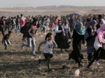 Manifestantes palestinos corren huyendo de los gases lacrimógenos lanzados por los israelíes