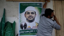 Un hombre cuelga un cartel con la foto de Al Batsh Un hombre cuelga un cartel con la foto de Al Batsh