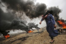 Una palestina lanza una piedra hacia la valla