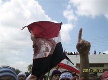 Un manifestante sostiene una bandera siria ensangrentada.