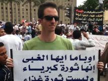 Ilan Grapel, en la plaza de la Liberación del Cairo, con una pancarta en árabe.