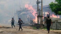 Policías de Myanmar andan entre casas incendiadas. Policías de Myanmar andan entre casas incendiadas.