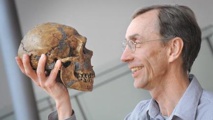 Un hombre sostiene un cráneo de Neandertal Un hombre sostiene un cráneo de Neandertal