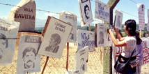 Cuelgan carteles con fotos de desaparecidos en lo que queda de la colonia, en Chile.