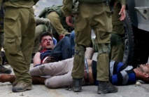 Soldados israelíes detienen a manifestantes palestinos heridos durante los enfrentamientos cerca de Bet El y Ramalá