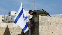 Un soldado israelí retira la bandera israelí en Hebrón