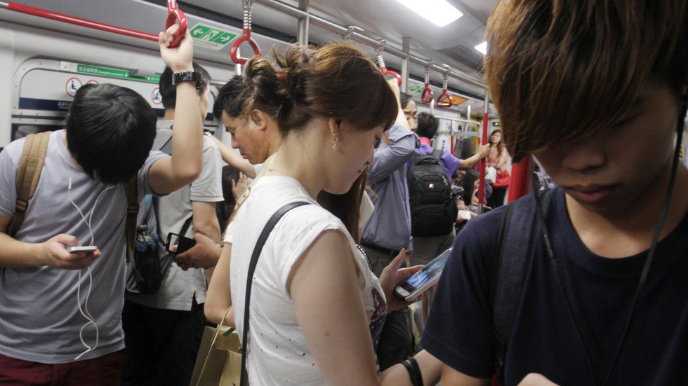 Chinos mirando sus teléfonos en el metro Chinos mirando sus teléfonos en el metro