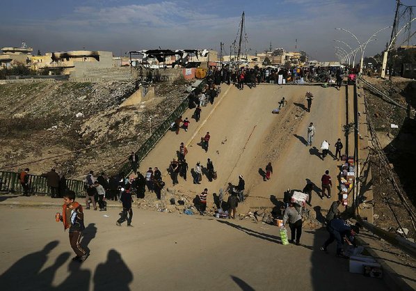 Iraquíes cruzando un puente destruido por los milicianos de Daesh en uno de los barrios de la parte este de Mosul