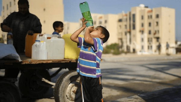 Un niño bebe agua del grifo en Gaza