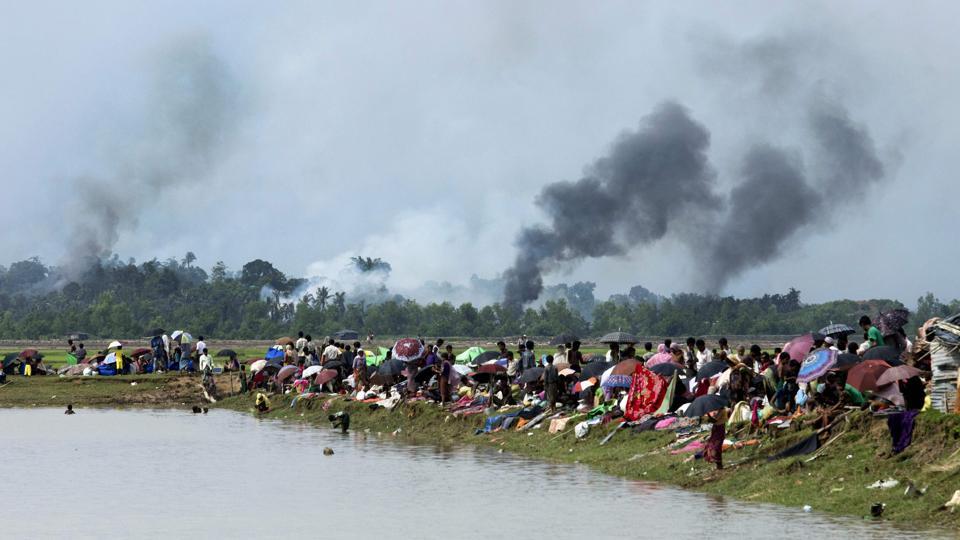 El humo sube de un pueblo incendiado detrás de unos refugiados