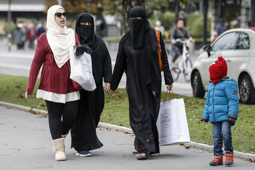 Una mujer con hiyab camina con dos mujeres con niqab.