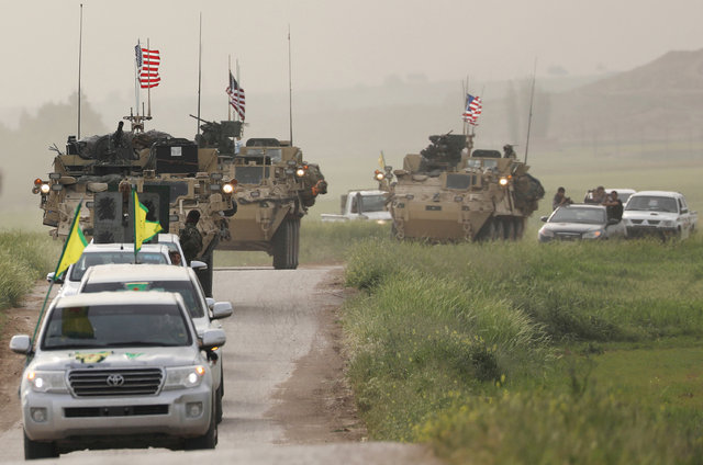 Vehículos con la bandera amarilla de la milicia kurda YPG seguidos de vehículos militares con la bandera estadounidense