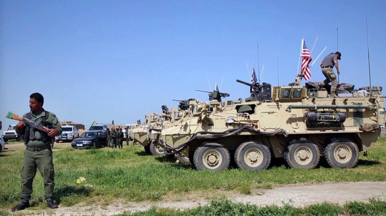 Un miliciano kurdo al lado de vehículos militares estadounidenses