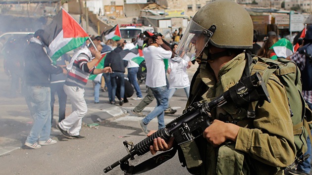 Un soldado israelí y manifestantes palestinos