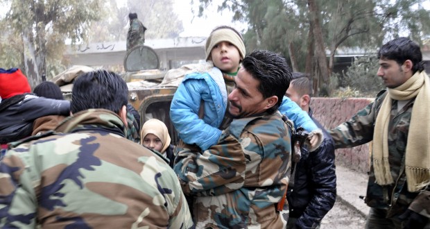 Un soldado sirio lleva a un niño