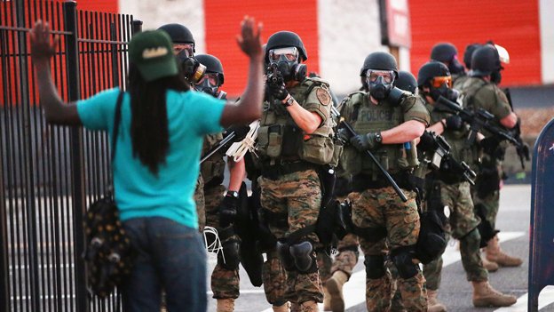 Una manifestante negra levanta las manos ante los policías blancos en Ferguson el año pasado.