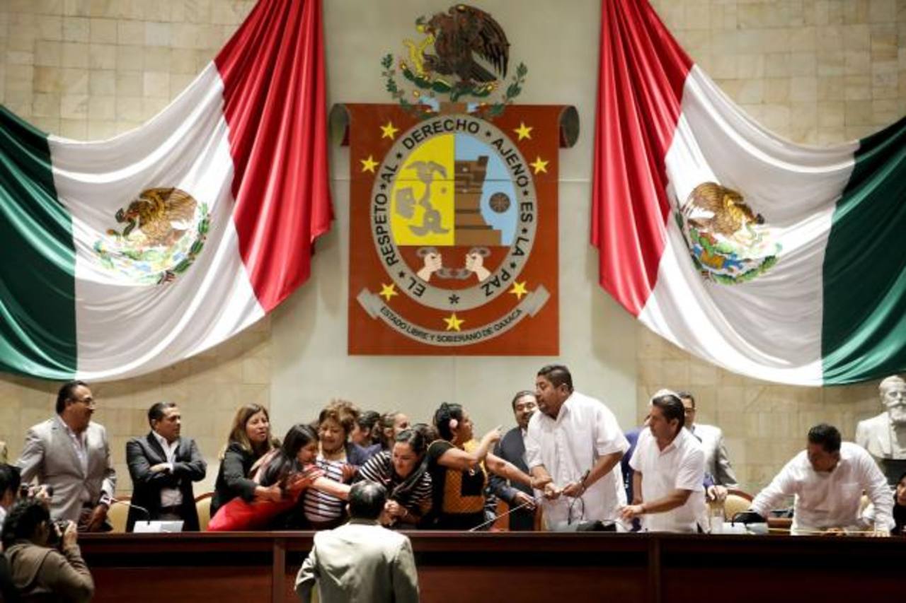 Diputados del PRI ocupando la mesa presidencial en Oaxaca