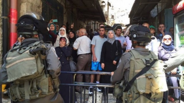 Soldados israelíes frente a palestinos en una calle bloqueada en Jerusalén