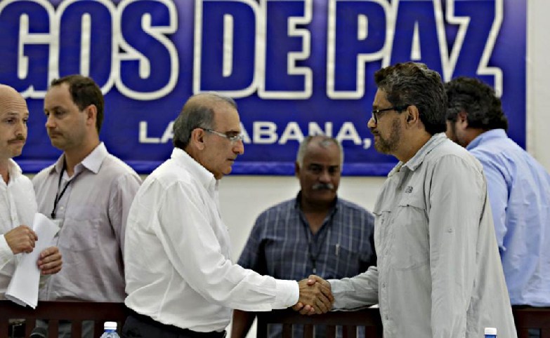 El jefe de la delegación del gobierno, Humberto De La Calle-a la izquierda-le da la mano al jefe de la delegación de las FARC, Iván Márquez