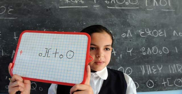 Una niña sostiene una pizarra con una palabra escrita en alfabeto tamazight